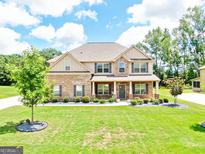 Inviting two-story home boasts a manicured lawn and a mix of brick and siding exterior with a covered front porch at 117 Elkins Blvd, Locust Grove, GA 30248