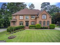 Impressive two-story brick home featuring a manicured lawn, and mature landscaping at 1952 Sugarstone Dr, Lawrenceville, GA 30043