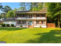 Charming two-story home with double balconies, shutters, a brick facade, and a well-manicured lawn at 103 Chipstone Ct, Peachtree City, GA 30269