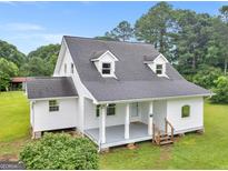 Charming home featuring a covered front porch, gray roof, and light gray siding, surrounded by lush landscaping at 778 Leguin Mill Rd, Locust Grove, GA 30248