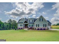Stunning two-story home with light green siding, stone accents, and beautifully landscaped front yard at 3076 East Lake Rd, Mcdonough, GA 30252