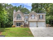 Inviting two-story home with a well-manicured lawn, two car garage, and charming architectural details at 400 Kenny Ln, Temple, GA 30179