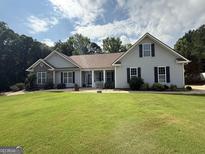 Charming single-story home with gray siding, stone accents, mature landscaping, and a lush green lawn at 1422 New Holland Cir, Mcdonough, GA 30252