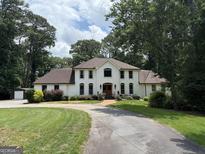 Stately two-story white brick home with a beautiful lawn, garden beds, and a long driveway at 1908 Musket Ct, Stone Mountain, GA 30087