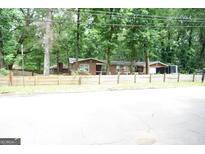 Charming single-story brick home with mature trees and a rustic wooden fence at 3010 Waters Rd Sw, Atlanta, GA 30354