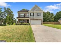 Charming two-story home featuring stone accents, a well-manicured lawn, and a spacious two-car garage at 140 Canyons, Hampton, GA 30228