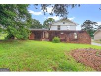 View of the front of a charming two-story home with a unique brick wall and landscaped yard at 5436 Ahyoka Dr, Morrow, GA 30260