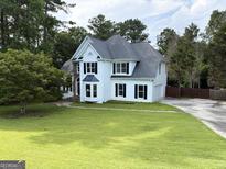 Classic two-story home with a well-manicured lawn and mature trees at 2325 Lochinver Sw Ln, Conyers, GA 30094