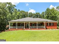 Charming red brick home features a long porch, white columns, and lush green lawn at 543 Wynn Rd, Mcdonough, GA 30252