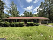 Charming brick home with a lush green lawn and a convenient covered carport at 402 Stone St, Oxford, GA 30054