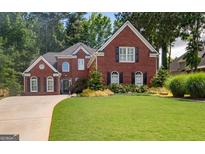 Charming two-story brick home with manicured lawn and mature trees providing shade at 220 Lavender Oasis, Peachtree City, GA 30269