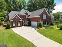 Charming two-story red brick home with a well-manicured lawn, driveway and attached two-car garage at 220 Lavender Oasis, Peachtree City, GA 30269