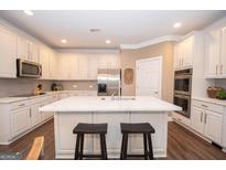 Well-lit kitchen with white cabinets, stainless steel appliances, and an island with a white countertop at 220 Lavender Oasis, Peachtree City, GA 30269