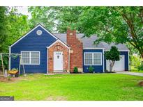 Charming blue cottage-style home with brick chimney and well-manicured lawn featuring a swing set at 6391 Katherine St, Douglasville, GA 30134