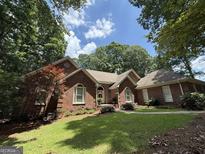 Stunning brick home with lush landscaping and mature trees on a sunny day at 280 Emerald Lake Dr, Fayetteville, GA 30215