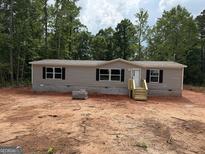 Newly constructed single-Gathering home featuring gray siding, black shutters, and surrounded by a wooded area at 436 Laurel Trce, Carrollton, GA 30116