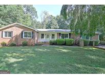 Charming brick home featuring a well-manicured front yard and neatly trimmed landscaping at 110 Heatherwood Dr, Fayetteville, GA 30215