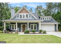 Charming home featuring a welcoming front porch with rocking chairs and well-manicured landscaping at 9148 Tarnwood Dr, Villa Rica, GA 30180