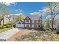 Charming brick-and-brown-trim home with an attached two-car garage and a well-maintained lawn under a blue sky at 3797 Churchill Sw Dr, Marietta, GA 30064