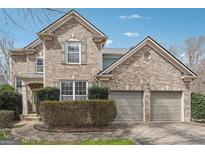 Two-story brick home featuring an attached two-car garage and manicured landscaping at 6448 Mobilis Ct, Sugar Hill, GA 30518