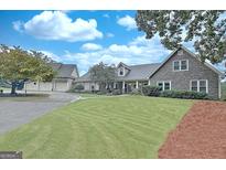 Expansive front yard showing the stone and siding exterior of the home under a partly cloudy sky at 676 Mcbride Rd, Fayetteville, GA 30215