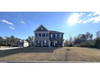 Charming two-story home with manicured lawn, and brick and siding facade under a bright, sunny sky at 5257 Shorthorn Way, Powder Springs, GA 30127