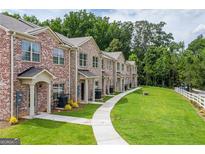View of brick townhomes with manicured lawns and a concrete walkway leading to each unit's front entrance at 3358 Mount Zion Rd, Stockbridge, GA 30281
