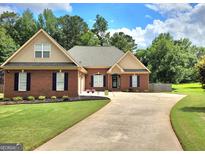 Charming brick home featuring a manicured lawn, long driveway, and traditional architectural details at 223 Overland Trl, Mcdonough, GA 30252