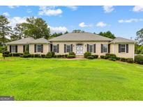 Charming single-story home with a well-maintained lawn and classic architectural details at 115 Fernway Dr, Fayetteville, GA 30214
