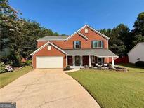 Charming two-story brick home featuring a well-maintained front lawn and attached two-car garage at 5388 Silver Springs Dr, Sugar Hill, GA 30518