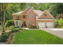 Elegant brick home featuring a well-manicured lawn and a two-car garage in a lush, green setting at 3245 Bywater Trl, Roswell, GA 30075