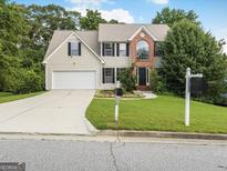 Charming two-story home featuring a well-manicured lawn, brick accents, and an attached two-car garage at 942 Marta Crane Dr, Lawrenceville, GA 30045