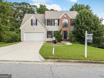 Charming two-story home featuring a manicured lawn, a two-car garage and a traditional brick facade at 942 Marta Crane Dr, Lawrenceville, GA 30045