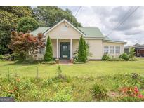 Charming home boasts a lush green lawn, colorful flowerbeds, and healthy landscaping, creating an inviting curb appeal at 178 S Old Highway 27, Roopville, GA 30170