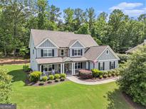 Inviting two-story home featuring manicured lawn, stone accents, and a charming front porch with rocking chairs at 185 Discovery Lake Dr, Fayetteville, GA 30215