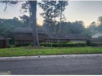 Two-story house featuring a neatly maintained lawn and hedges along the facade, nestled among mature trees at 4255 Glenda Dr, College Park, GA 30337