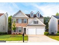 Charming two-story home featuring a brick and gray siding exterior with a two-car garage and well-manicured lawn at 8750 Redford Ln, Suwanee, GA 30024