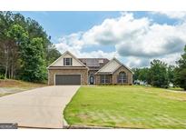 Charming brick home with a well-manicured lawn, attached two car garage and solar panels on the roof at 501 Llewellyn Ct, Jenkinsburg, GA 30234