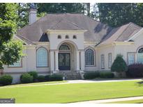 Elegant home featuring a well-manicured lawn and a stately entrance with a detailed archway and decorative wreaths at 433 Abbey Springs Way, Mcdonough, GA 30253