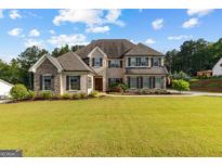 Impressive stone and brick home featuring a manicured lawn and classic architectural details at 150 Dean Dr, Tyrone, GA 30290