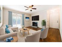 Cozy living room features a ceiling fan, fireplace, hardwood floors, and ample natural light at 503 Countryside Se Pl, Smyrna, GA 30080
