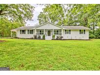 Charming single-story home with a well-manicured lawn and inviting covered front porch with trees nearby at 306 Tyrone Rd, Fayetteville, GA 30214