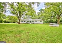 Charming one-story home featuring a beautifully landscaped yard with mature trees and a quaint exterior at 306 Tyrone Rd, Fayetteville, GA 30214