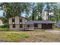 Two-story home featuring neutral siding, covered porch, attached garage, and surrounded by mature trees at 770 Four Winds Ln, Jonesboro, GA 30238