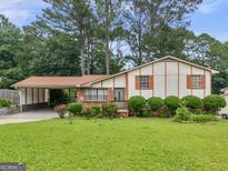 Charming single-Gathering home featuring a carport, mature trees, and a well-maintained front yard at 8310 Meridian Dr, Riverdale, GA 30274