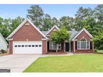 Charming brick home featuring manicured lawn, mature landscaping, and a two-car garage at 192 Sandhurst Ct, Suwanee, GA 30024