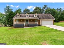 Charming home with a front porch, dormer windows, and well-maintained lawn and landscaping at 2000 Stacia Dr, Covington, GA 30016