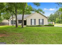 Charming single-story home with a well-manicured lawn and mature trees enhancing its curb appeal at 615 Coan Dr, Locust Grove, GA 30248