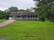 Charming single-story home featuring a full front porch with white railing and a spacious front yard at 1997 Villa Rica Hwy, Dallas, GA 30157