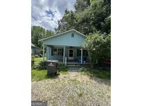 Charming single-story home featuring a quaint front porch, light blue siding, and an unkempt front yard at 8373 Chicago Ave, Douglasville, GA 30134